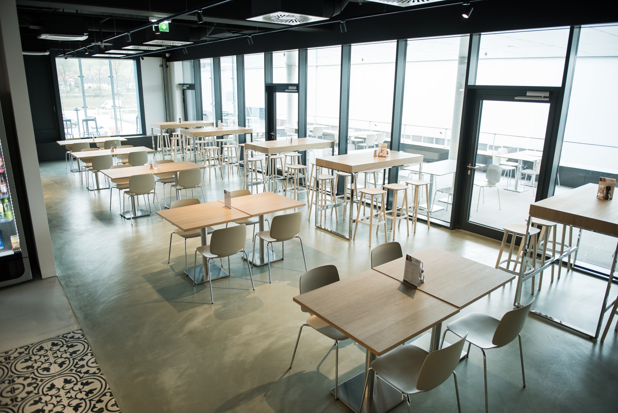 Kantine mit Besucherstühlen mit Holzschale und farblich passender Tischplatte sowie Tischbein aus Metall.