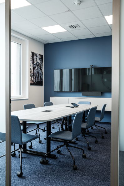 Moderner Konferenzraum bei Tractive mit blauer Wand, großem Tisch und Bildschirm, eingerichtet mit hali Möbeln.