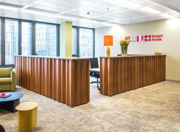 Moderner Empfangsbereich mit markanter Empfangstheke, Sitzgelegenheit und Corporate Branding an der Wand.