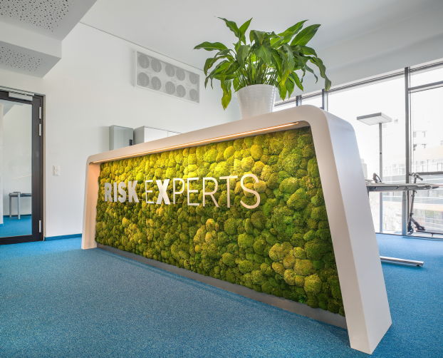 Moderne Rezeption mit beleuchteter Mooswand und integriertem Pflanzenelement als grüner Blickfang