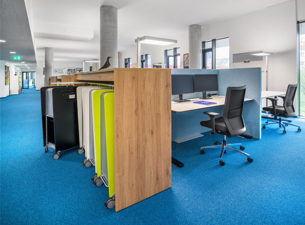 Großraumbüro mit doppelseitigen Arbeitsplätzen, Sichtschutz-Elementen und ergonomischen Drehstühlen