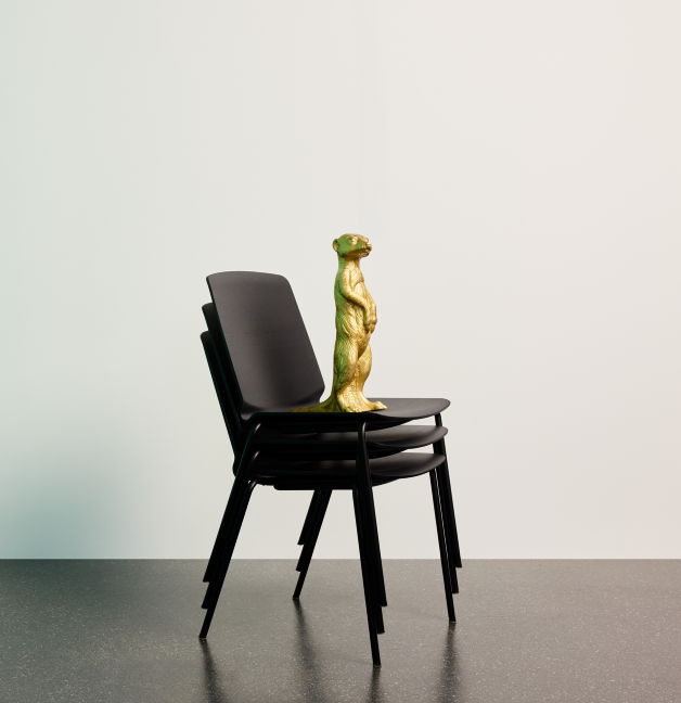 Gestapelte schwarze Curve Stühle mit goldenem Dekoelement.