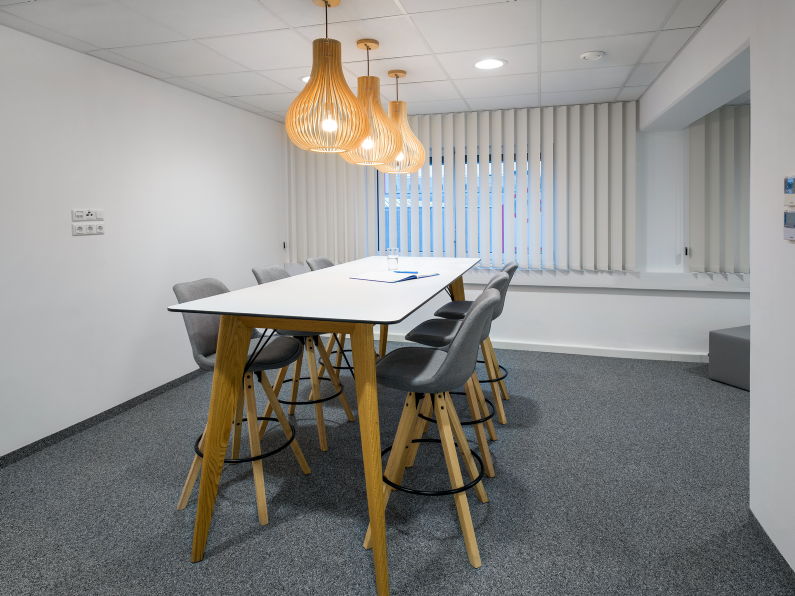 Weißer Hochtisch mit Holzgestell und gepolsterten Barhockern unter Designerlampen